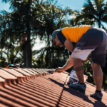 A roofing professional applying flexible pointing compound to the ridge caps of a tile roof in Byron Bay during a sunny day.