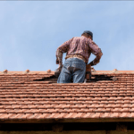 A professional local roof tiler in Bangalow inspecting broken tiles and performing an emergency roof leak repair in Ocean Shores.