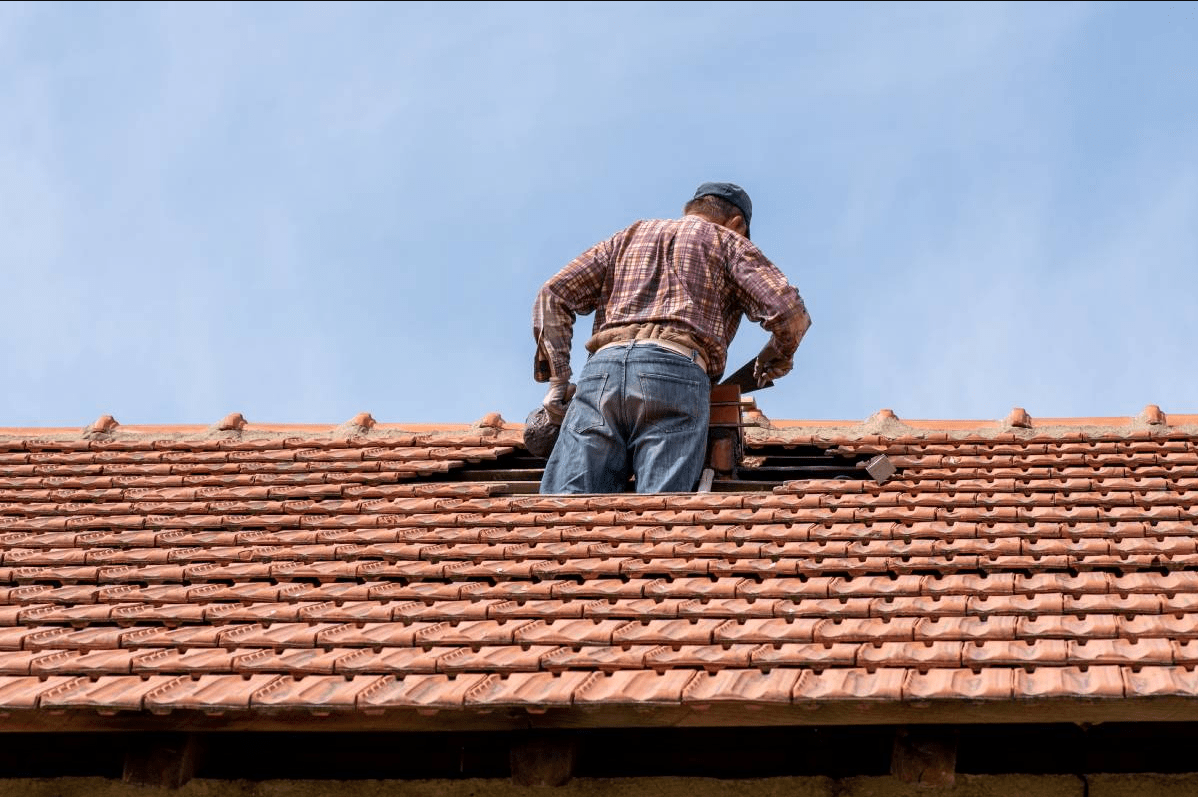 A professional local roof tiler in Bangalow inspecting broken tiles and performing an emergency roof leak repair in Ocean Shores.