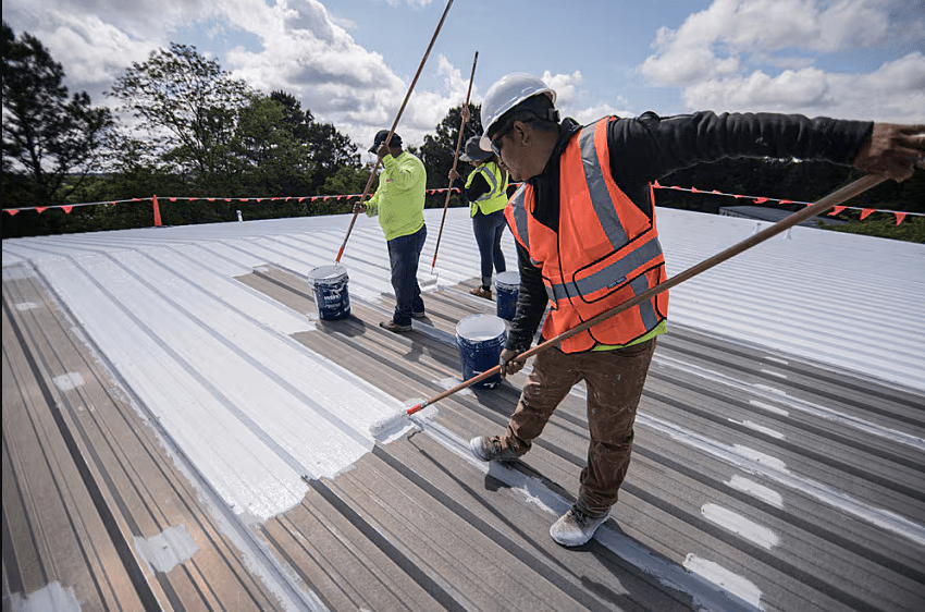 A professional roofing contractor applying a thick protective roof membrane coating to a residential home in Mullumbimby.